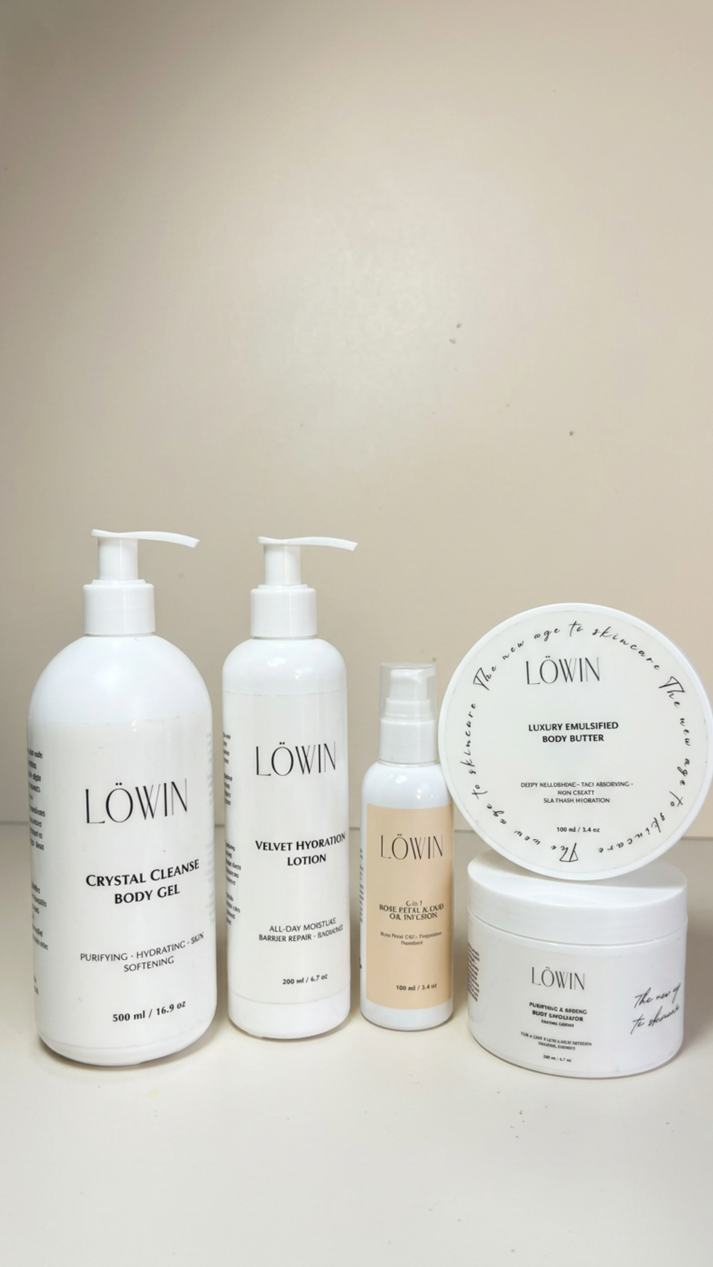 A set of five Löwin skincare and body care products arranged on a plain beige background, including body gel, lotion, face & body oil, boy scrub and emulsified body butter