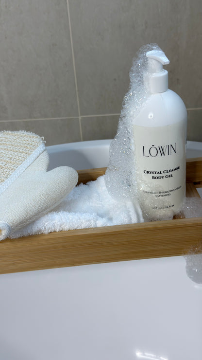Bottle of Löwin Crystal Cleansing Body Gel on a bath tray with a towel and scrubber.