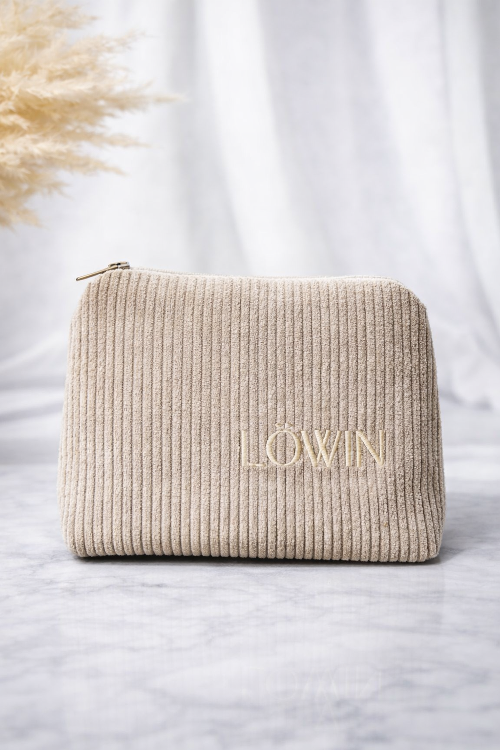 Beige embroidered toiletry bag with 'Löwin' branding on a light background